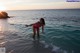 A woman in a pink bathing suit standing in the ocean.