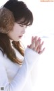 A woman in a white sweater and fur ear muffs praying.