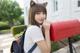 A young woman with a cat ears on her head holding a red mailbox.