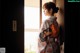 A woman in a kimono standing by a window.