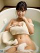 A woman in a bathtub with a towel wrapped around her body.