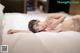 A woman laying on a bed in a white lingerie.