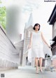 A woman in a white dress walking down a street.