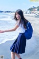 A woman in a school uniform is walking on the beach.