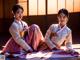 A couple of women sitting on top of a wooden floor.