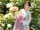 A woman in a pink and blue dress holding a bouquet of flowers.